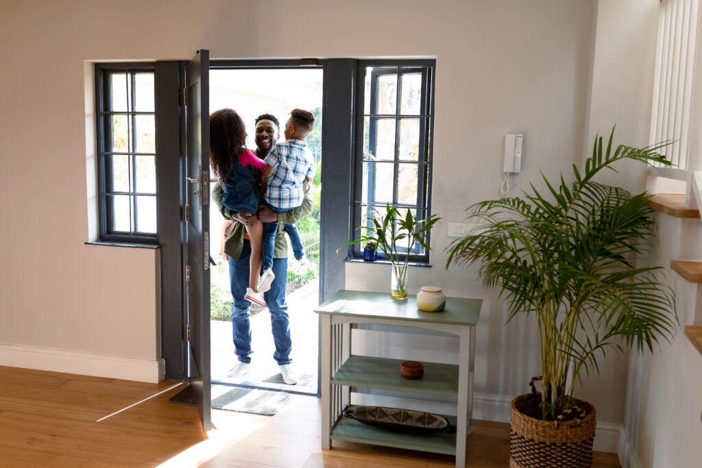 Father arriving home greeted by two happy children in a secure, welcoming smart home environment
